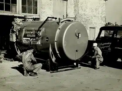 Workers installing a Cleaver-Brooks boiler outside a facility, with a Refrigeration Equipment Co. truck nearby.